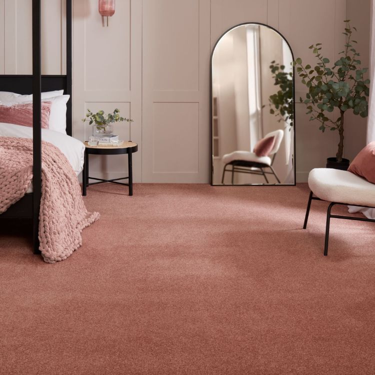 A rose coloured sparkle carpet laid in a bedroom with four poster bed, mirror and chair.